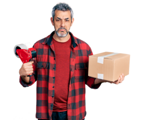 Middle age hispanic with grey hair holding packing tape and cardboard box depressed and worry for distress, crying angry and afraid. sad expression.