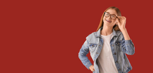 Portrait of teenage girl in jeans jacket on red background with space for text
