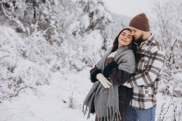 Portrait of a young happy and loving couple having fun in a snowy forest