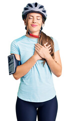 Beautiful caucasian young woman wearing bike helmet smiling with hands on chest with closed eyes and grateful gesture on face. health concept.