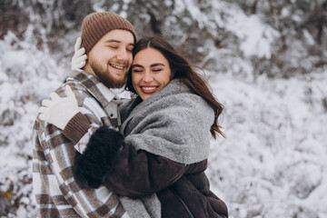 Obraz premium Portrait of a young happy and loving couple having fun in a snowy forest