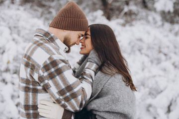 A young happy and loving couple walking in a winter snowy forest in the mountains