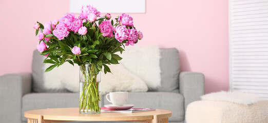 Vase with pink peonies on coffee table in living room