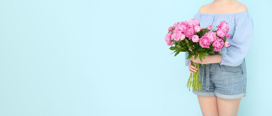 Woman holding bouquet of pink peonies on light blue background with space for text