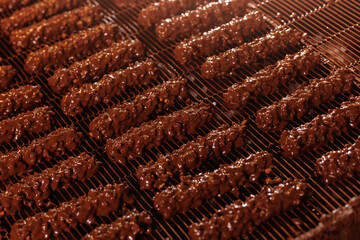 Waffles with nuts are coated with chocolate on conveyor. Production line of food factory, concept modern bakery plant