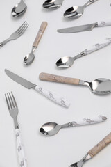 Set of stainless steel cutlery with plastic handles on white background