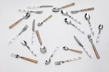 Frame made of stainless steel cutlery with plastic handles on white background