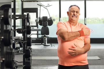 Mature man in sportswear holding injured shoulder