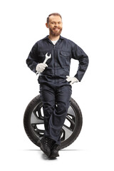 Car mechanic holding a wrench and sitting on a tire