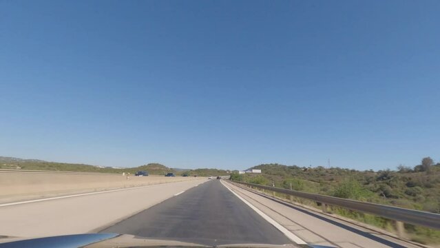 First person view, FPV, from dashcam of car driving along the Algarve Coast in Portugal, driving on the highway. Road trip video in POV, with blue sky