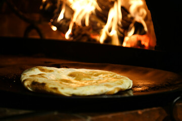 Unleavened bread served in wooden board isolated on table side view of arabic food