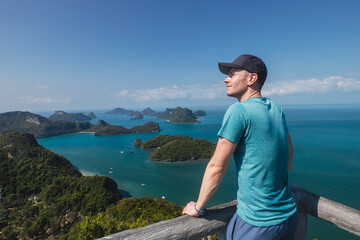 Happy man is enjoying amazing view from top of hill. Group of tropical islands in sea near Koh...