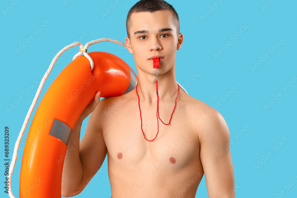 Wall mural Male lifeguard with ring buoy whistling on blue background