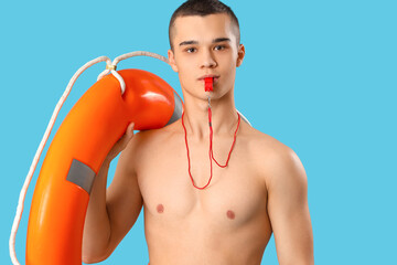Male lifeguard with ring buoy whistling on blue background