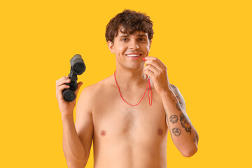 Male lifeguard with whistle and binoculars on yellow background