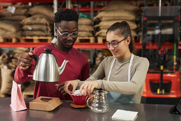 Waist up portrait of two young people brewing coffee in small artisanal coffee manufactory, copy space