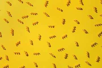 Composition with uncooked elbow pasta on yellow background