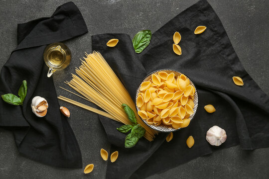 Composition with different uncooked pasta and spices on dark background