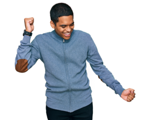 Young handsome hispanic man wearing casual sweatshirt dancing happy and cheerful, smiling moving casual and confident listening to music