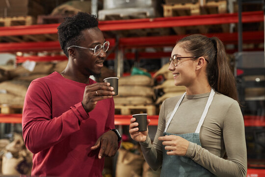 Waist up portrait of two smiling young people tasting coffee in small manufactory, copy space
