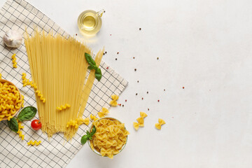 Composition with different uncooked pasta and spices on light background