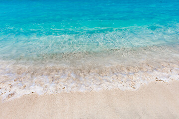 Fototapeta na wymiar Sea surf turquoise with splashes on sandy beach close-up