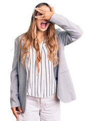 Young beautiful blonde woman wearing call center agent headset peeking in shock covering face and eyes with hand, looking through fingers with embarrassed expression.