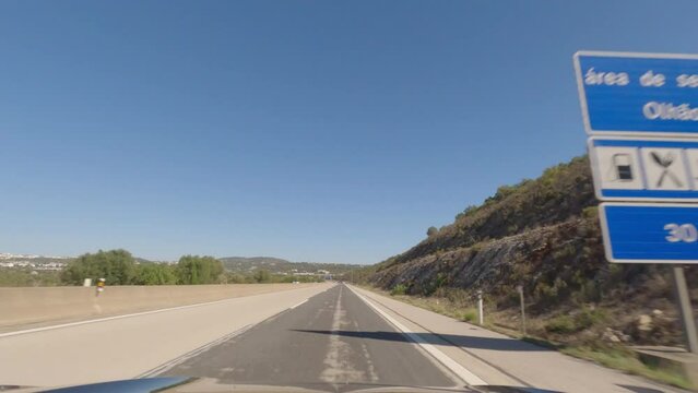 First person view, FPV, from dashcam of car driving along the Algarve Coast in Portugal, driving on the highway. Road trip video in POV, with blue sky