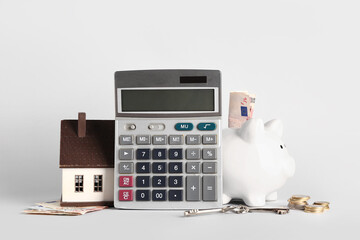 Calculator, house model, keys, piggy bank and money on light background. Mortgage concept
