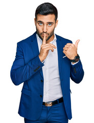 Young hispanic man wearing business jacket asking to be quiet with finger on lips pointing with...