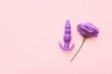 Purple anal plug from sex shop and beautiful eustoma flower on pink background