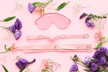 Sex toys and beautiful flowers on pink background