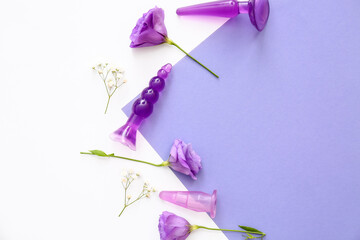 Anal plugs from sex shop and beautiful flowers on color background