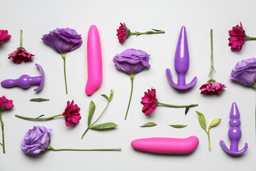 Different sex toys and beautiful flowers on light background