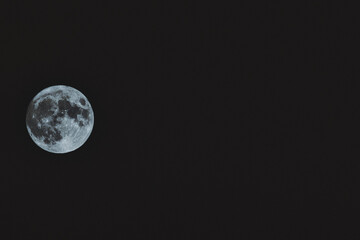 Naklejka na ściany i meble Full moon close up photo. Close up of full Luna. Detail of moon surface. Isolated background. Full moon closeup showing the details of the lunar surface. The Moon isolated on a black. Explorer space