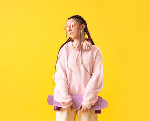 Young woman with dreadlocks and skateboard on yellow background