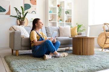 Young woman with dreadlocks using tablet computer at home