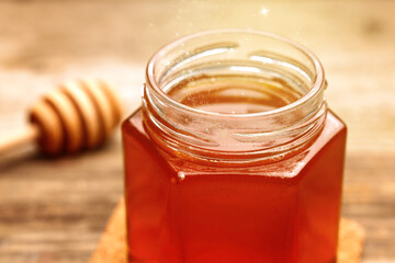 Natural honey in glass jar under sunlight, closeup - obrazy, fototapety, plakaty