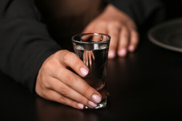 Woman with shot of cold vodka on table in bar, closeup