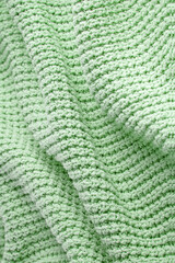 Turquoise green blanket in a large coarse knit with folds. Backdrop for design