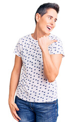 Fototapeta premium Young woman with short hair wearing casual clothes smiling with happy face looking and pointing to the side with thumb up.