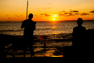 Silhouette of an unidentified person playing the Berimbau against the sunset.