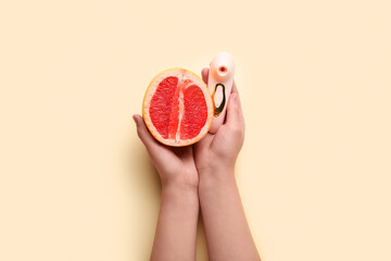 Woman with vibrator and grapefruit on beige background