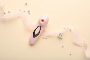 Vibrator with flowers and ribbon on beige background