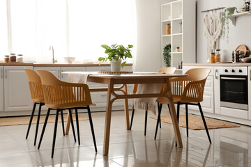 Interior of light kitchen with white counters and dining table
