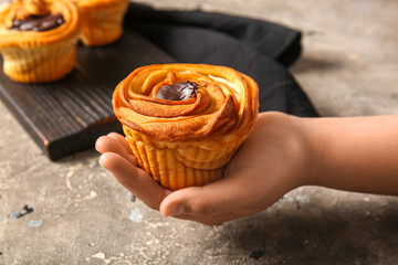 Woman holding tasty cruffin with chocolate on grey background