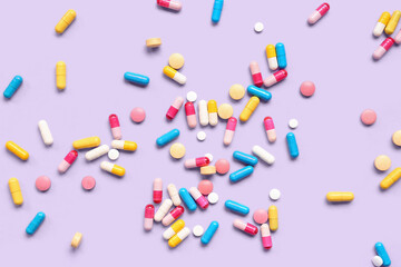 Many different pills on lilac background