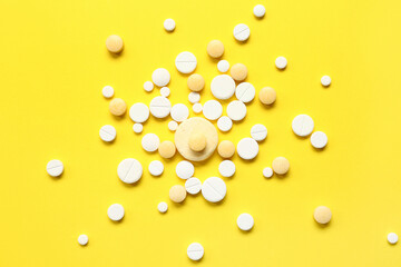 Many different pills on yellow background