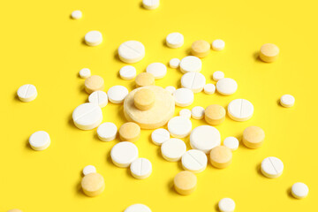Many different pills on yellow background