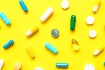 Many different pills on yellow background